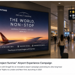Large Qantas Project Sunrise digital billboard inside a modern airport terminal with travelers walking nearby.